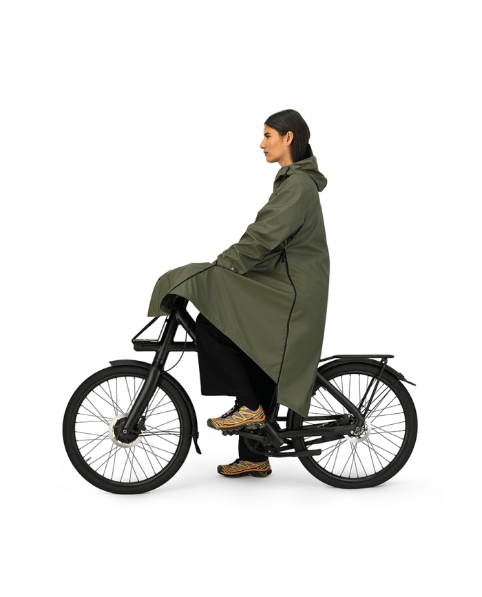 vrouw op fiets met maium regenjas van gerecyclede petflessen in de kleur army green groen uitgevouwen tot regenponcho zijaanzicht
