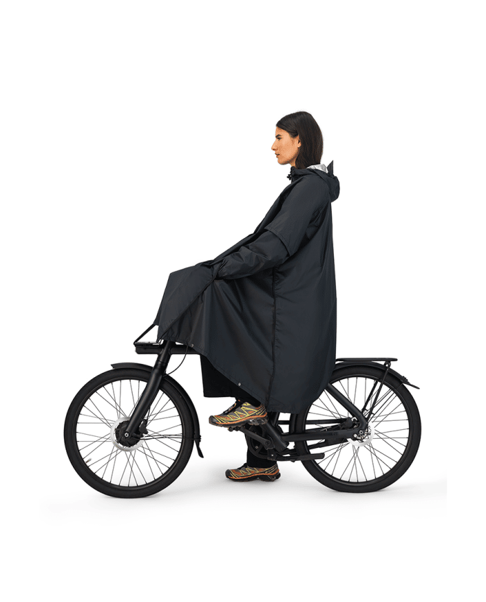vrouw op fiets met de maium regenponcho van gerecyclede petflessen in de kleur black uitgevouwen zijaanzicht