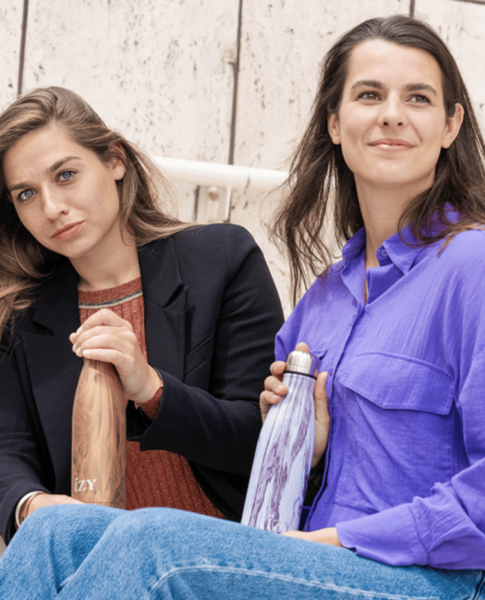 2 vrouwen poseren beide met een thermosfles design van IZY Bottles op hun schoot