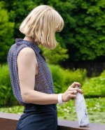 zij aanzicht van een vrouw in een park met een thermosfles marmer wit van izy bottles in haar hand