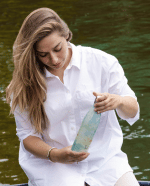 vrouw aan het water kijkend naar de thermosfles marmer groen van izy bottles in haar handen