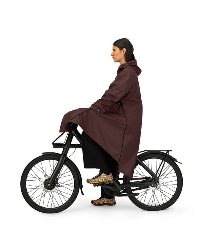 vrouw met maium regenjas van gerecyclede petflessen in de kleur bitter chocolate op fiets